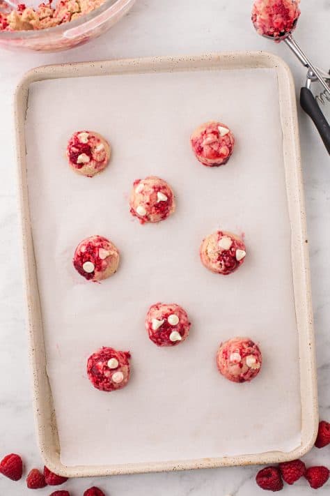Raw Raspberry White Chocolate Chip Cookies on a lined baking sheet.