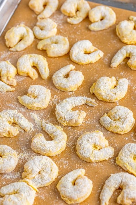 Flour coated raw shrimp on a sheet pan lined with parchment paper.