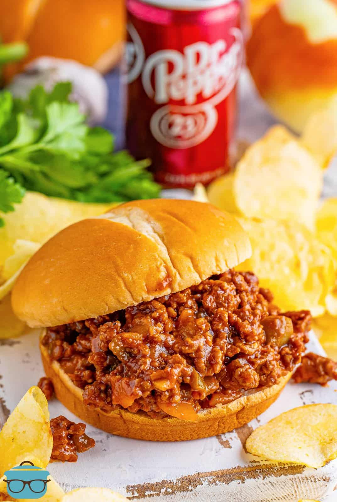 A white serving plate with Dr Pepper Sloppy Joes and a side dish behind it.