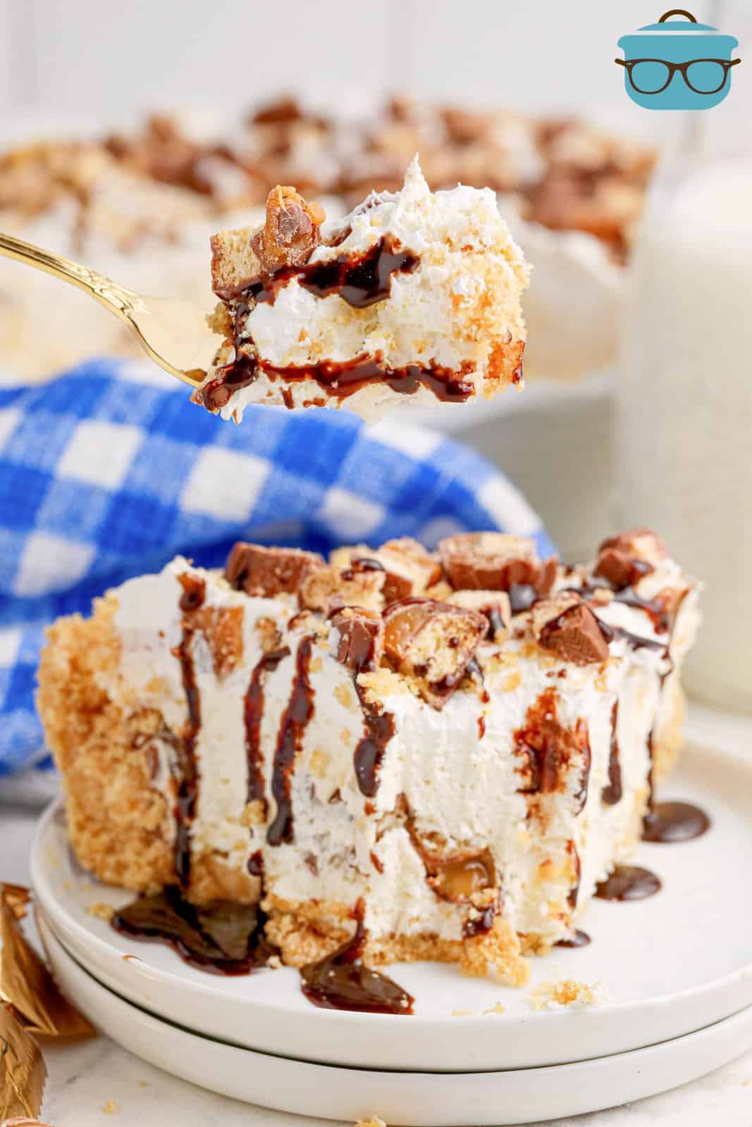 A fork holding a bite of No Bake Twix Pie above a slice of it.