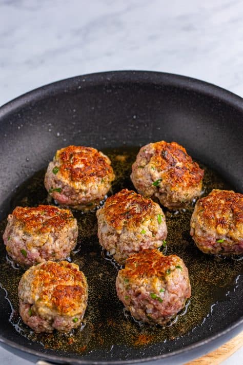 Browned meatballs in a skillet.