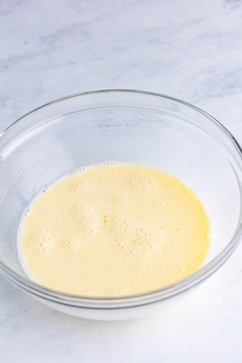 A mixing bowl with milk, egg, oil, and honey.