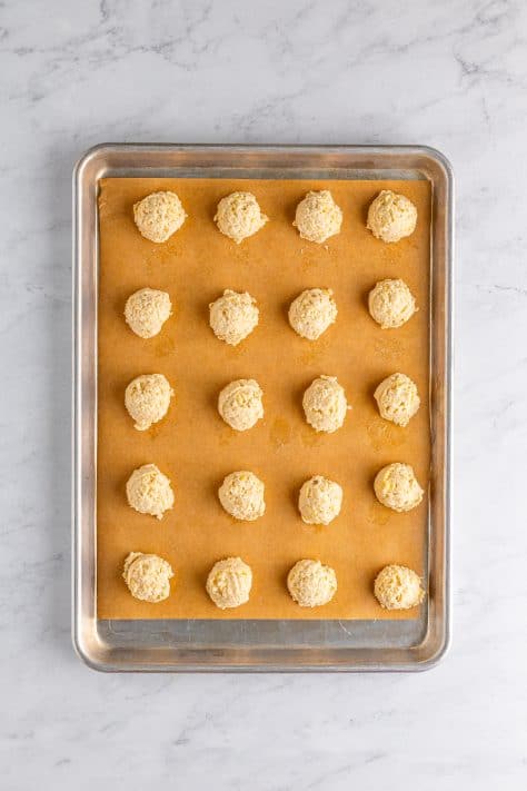 Potato chip cookie dough balls on a baking mat lined baking sheet.