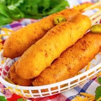 A pile of Jalapeno Cheddar Corn Dogs in a basket.