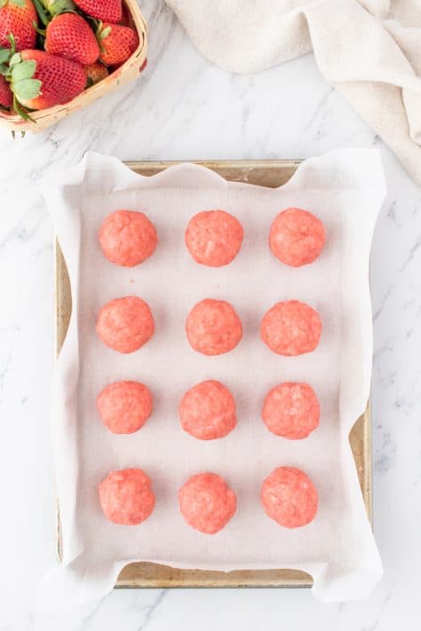 Strawberry Cake Balls on parchment lined baking sheet.