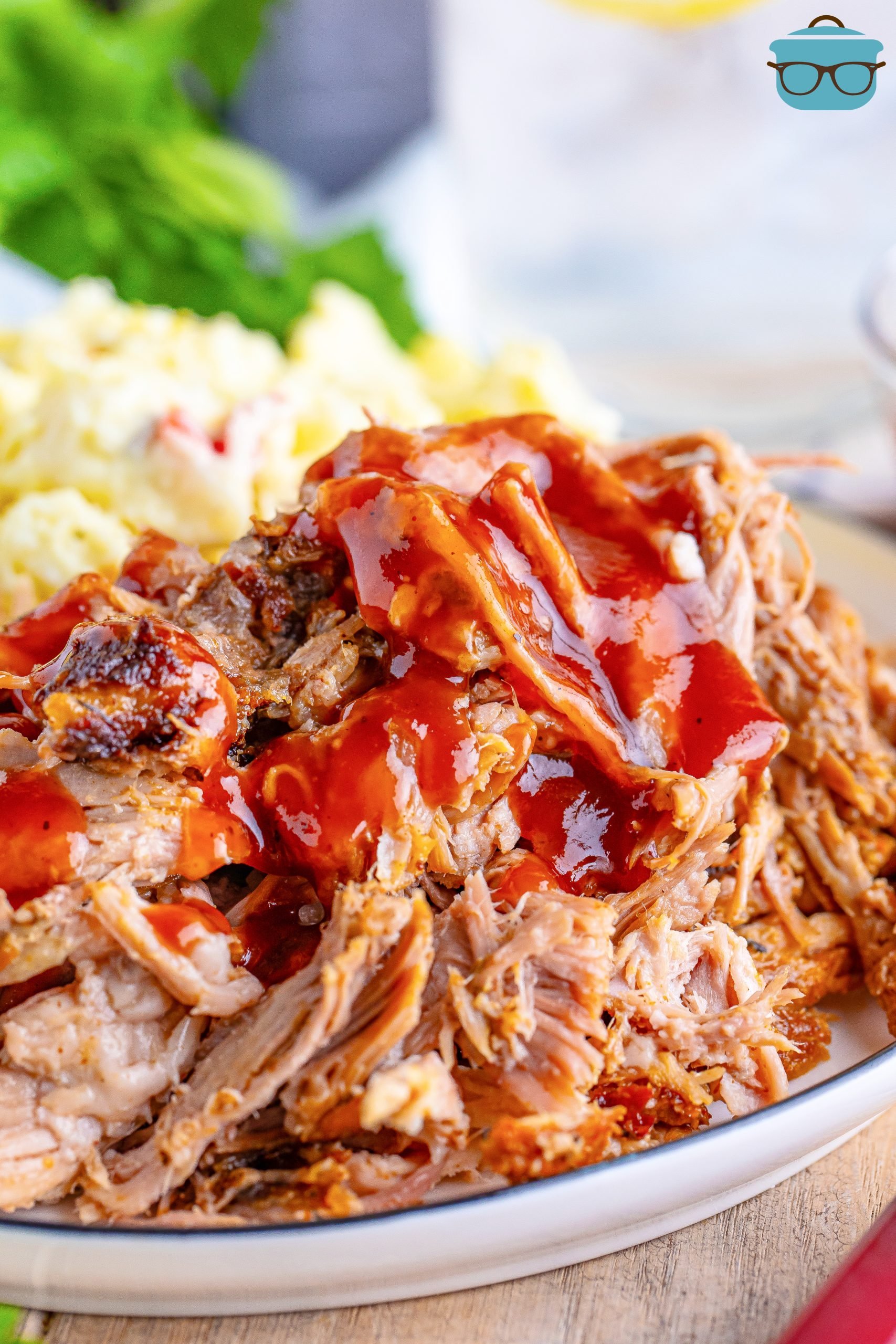 Close up looking at a plate of Oven Roasted Pulled Pork with bbq sauce drizzled on.