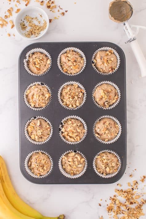 Chopped walnuts on top of the muffin batter in the muffin tin wells.