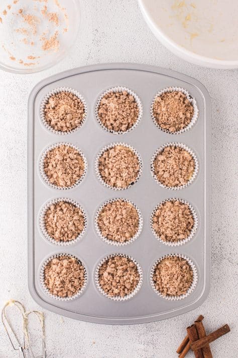Streusel topped Cinnamon Cake Mix muffins in a muffin pan.