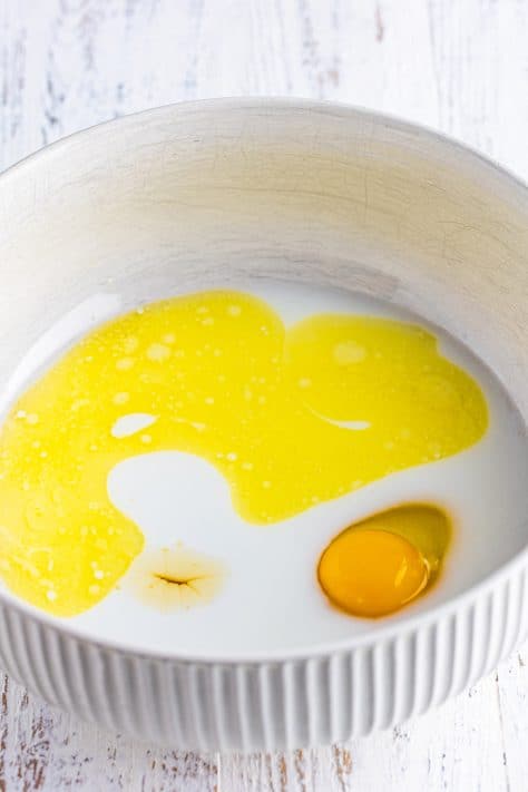 A mixing bowl with honey, egg, melted butter, milk, and water.