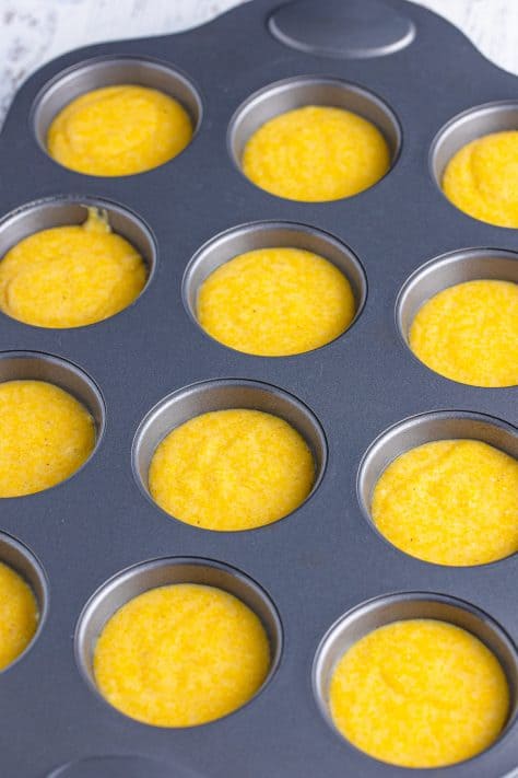 A muffin pan with the wells filled with Cornbread Muffin batter.