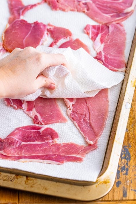 Ham slices being dried by paper towels.