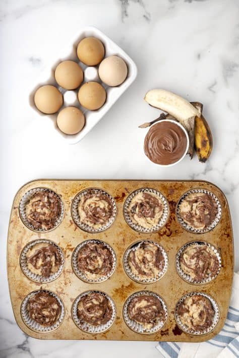 Nutella and banana muffin batter in a lined muffin tin.