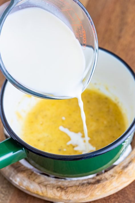 Milk being added to cheese mixture in a sauce pan.