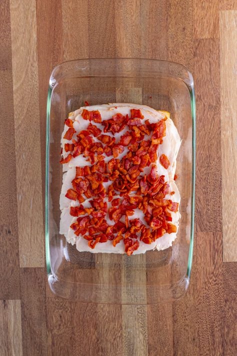 Crispy bacon pieces on top of turkey and rolls in a baking dish.