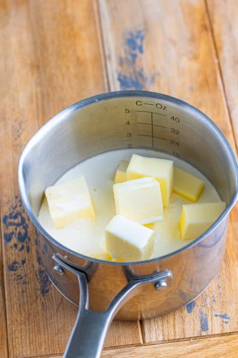 Butter cubes, chicken stock, and whipping cream in a pot.