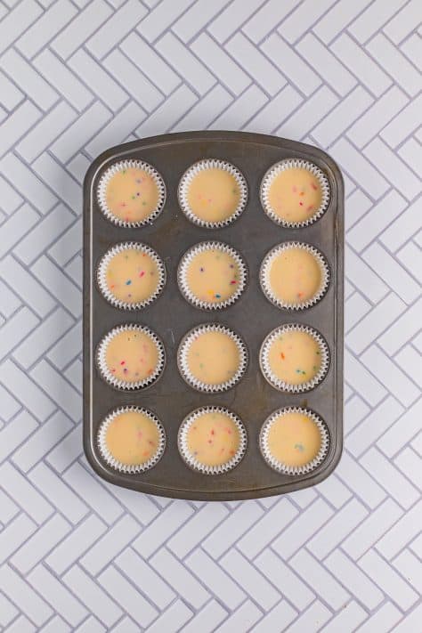 A lined cupcake tin with batter in each well.