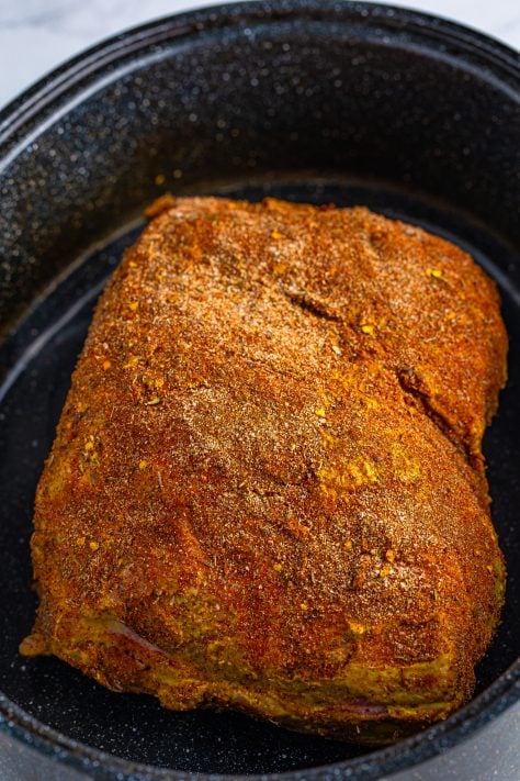 Seasoned pork in a roasting pan.