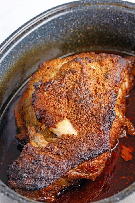 A baked pork shoulder in a pan.