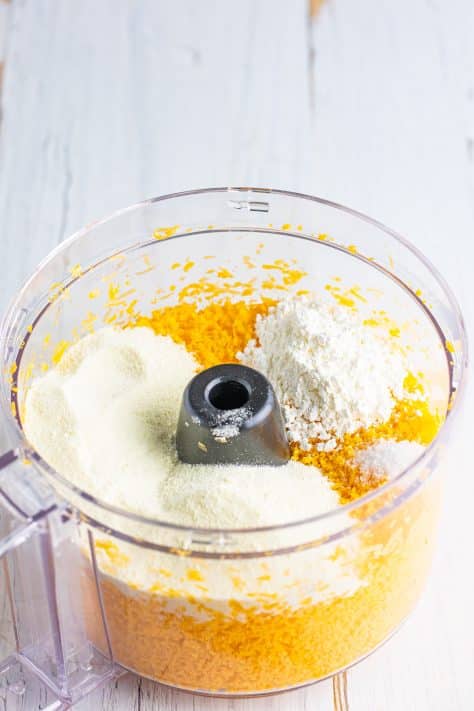 A food processor with cheese, water, powdered milk and cornstarch in it.