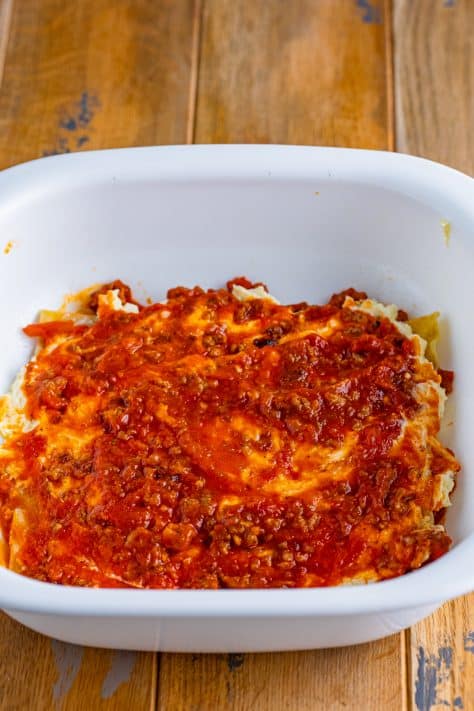More marinara on top of cheese and noodles.