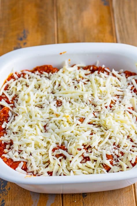 Mozzarella cheese on top of layered lasagna in a casserole dish.