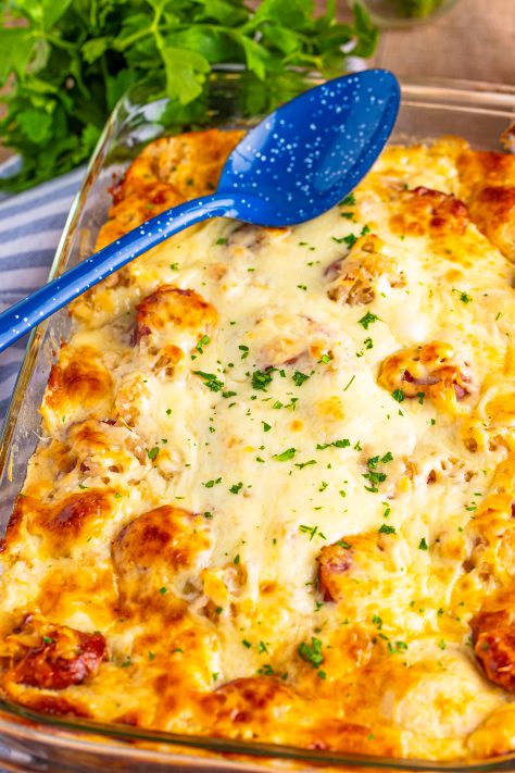 A fresh baked Pierogi Casserole with a serving utensil on top.