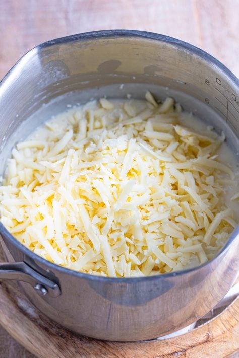 Mozzarella cheese on top of a butter milk sauce mixture in a pot.