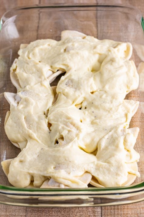 Pierogies with a cheese sauce on top in a baking dish.