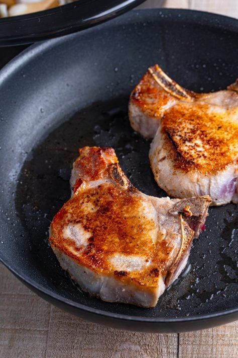 Seared pork chops in a pan.
