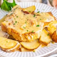Gravy smothered Crock Pot Pork Chops with Potatoes on a plate.