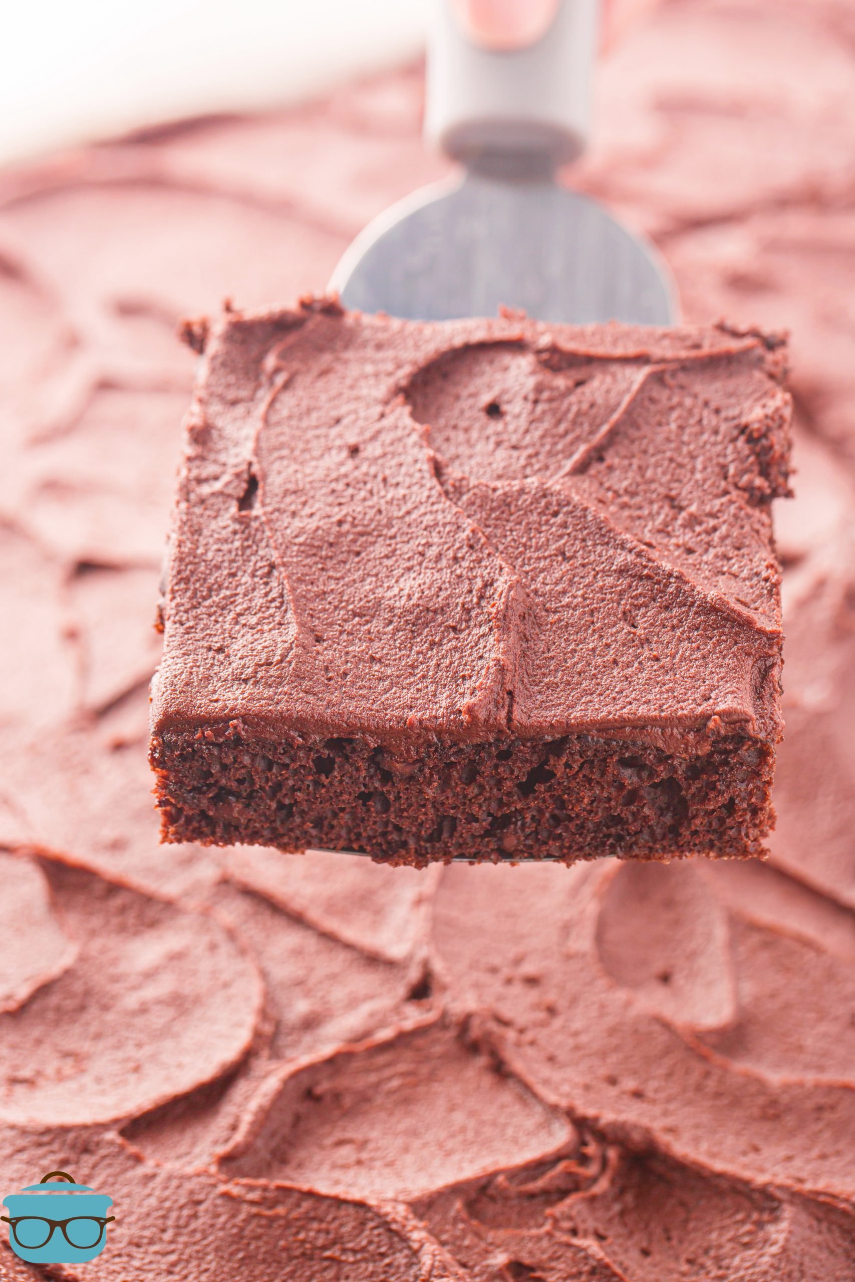 A serving utensil holding a slice of Chocolate Sheet Cake.