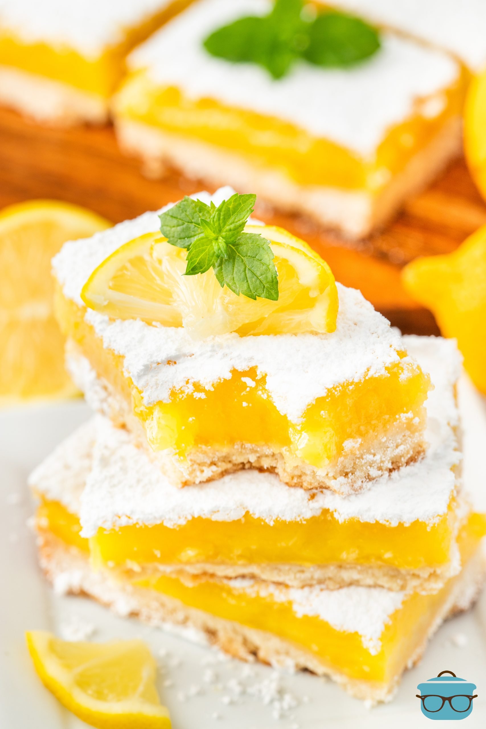 A small pile of Lemon Bars, the top with a bite missing.