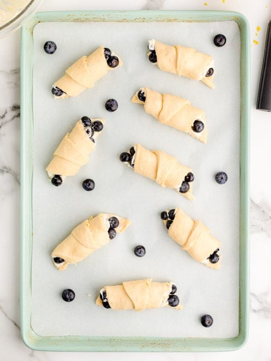 Unbaked Blueberry Cheesecake crescent rolls on a baking sheet.