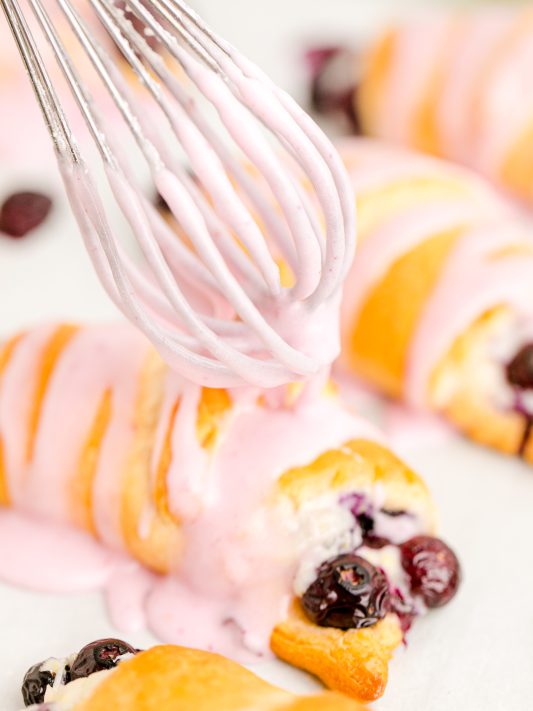 drizzling blueberry icing over crescent rolls.