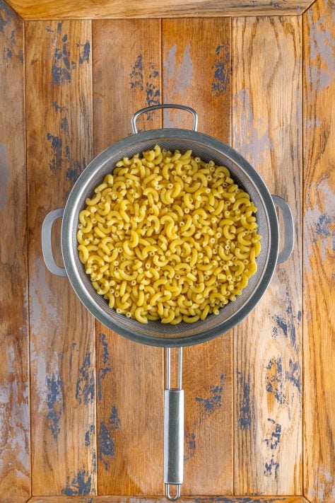 fully cooked macaroni noodles being drained in a colander.