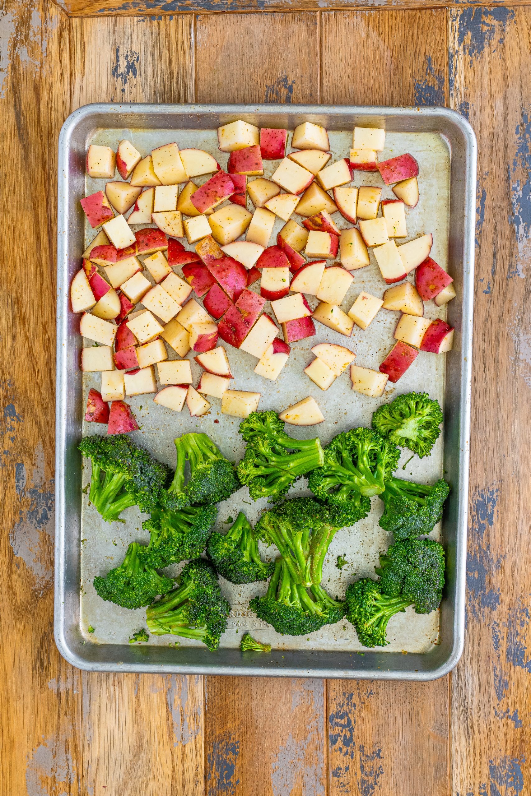 A sheet pan with broccolini and diced potatoes.