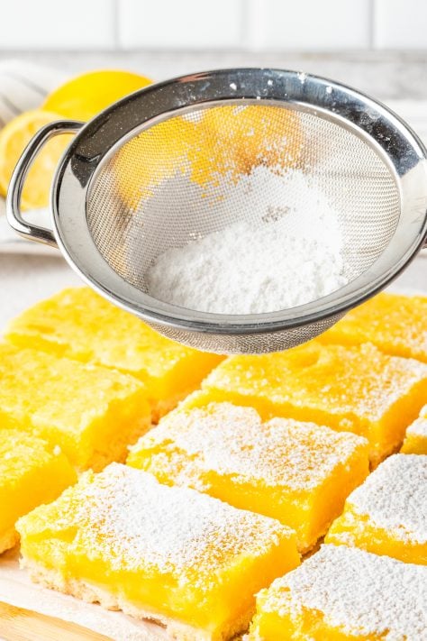 Powdered sugar being sifted on Lemon Bars.