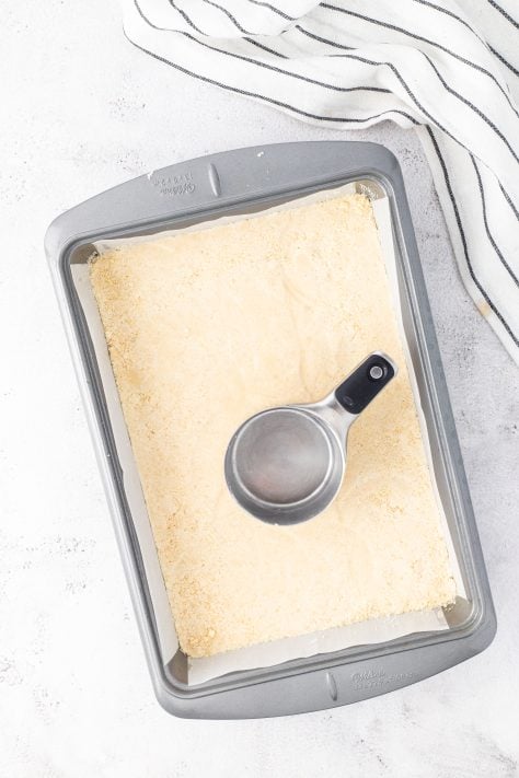 Unbaked Lemon Bar crust dough on a parchment lined baking pan.