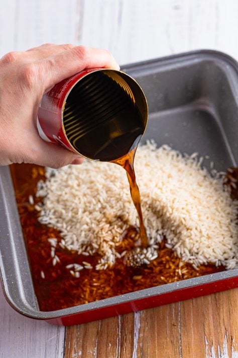 pouring beef broth into baking dish.