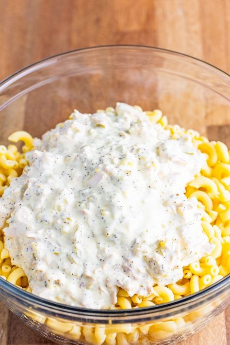 creamy mayonnaise mixture poured on top of cooked macaroni in a bowl.