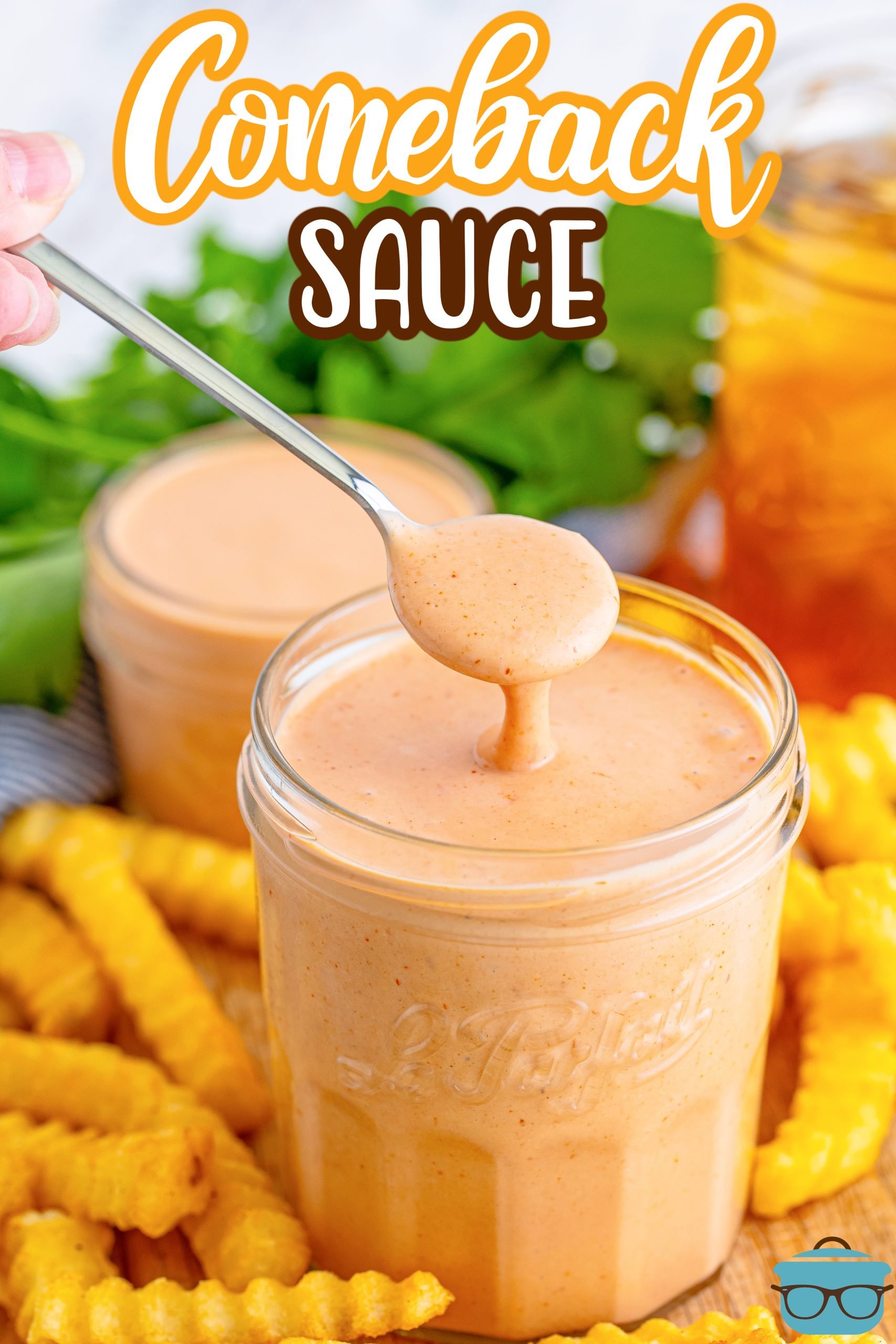 A spoon holding a scoop of Comeback Sauce above a jar.