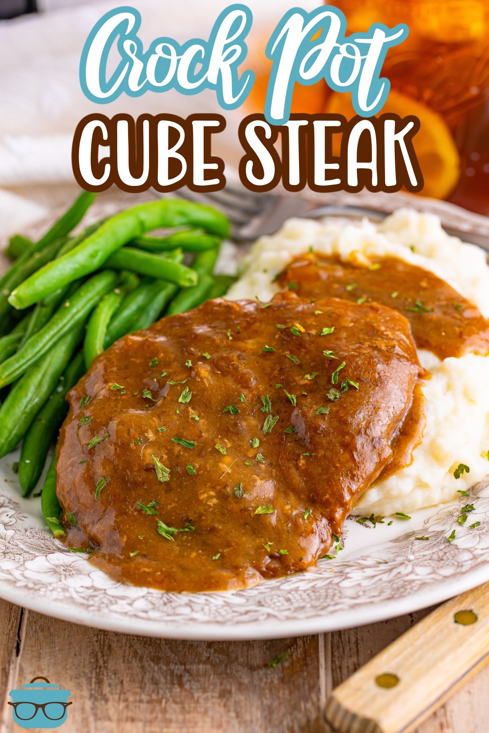 This image shows a cube steak with the gravy, served with mashed potatoes and green beans. 