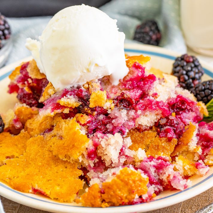 A scoop of ice cream on top of a large serving of Blackberry Cobbler.