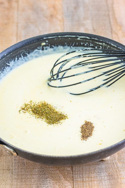 seasonings added to cream sauce with a whisk.