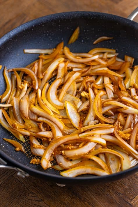 Sauteed slivered onions in a pan.