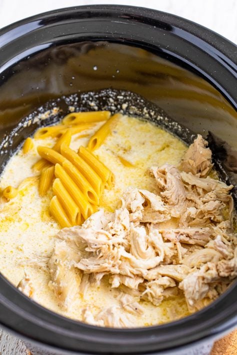 cooked penne pasta and shredded chicken added to cream sauce in slow cooker.