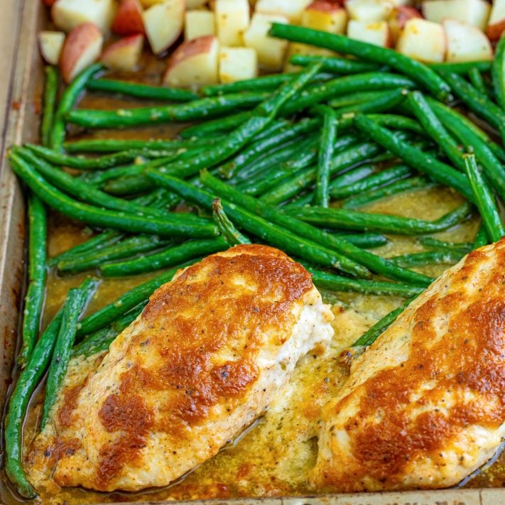 Looking down on a sheet pan with fresh green beans and Garlic Parmesan Chicken.
