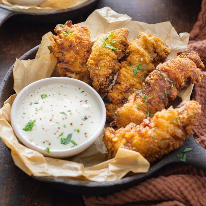 A few Chicken Fried Steak Fingers with a bowl of dipping sauce.