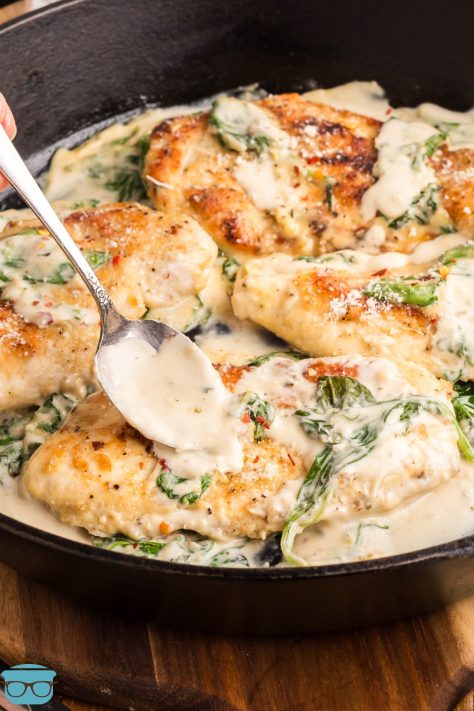 A spoon getting some of the sauce with the Chicken Florentine.
