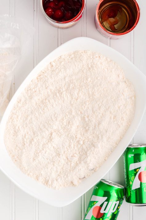 Cake mix being spread over pie filling.